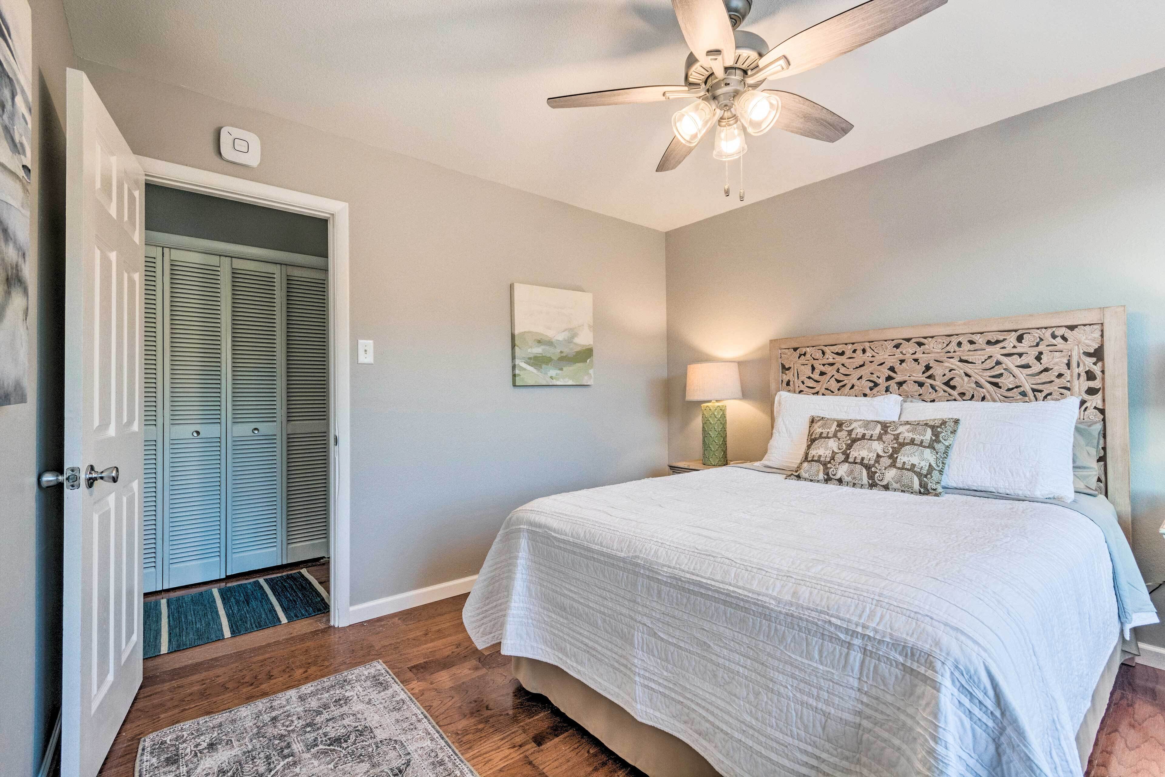 Ein Schlafzimmer mit einem Bett, einem Deckenventilator, einem Nachttisch, einer Lampe und einer Tür zu einem Schrank.