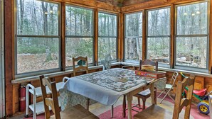 A cozy cabin interior with a large table covered with a puzzle, surrounded by wooden chairs. - East Otis Reservoir Cabin w/ Porch - Walk to Lake! (Otis)