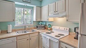 A kitchen with white cabinets, a microwave, a stove, and a sink. - Amelia Island Condo w/ Pool & Beach Access! (Fernandina Beach)