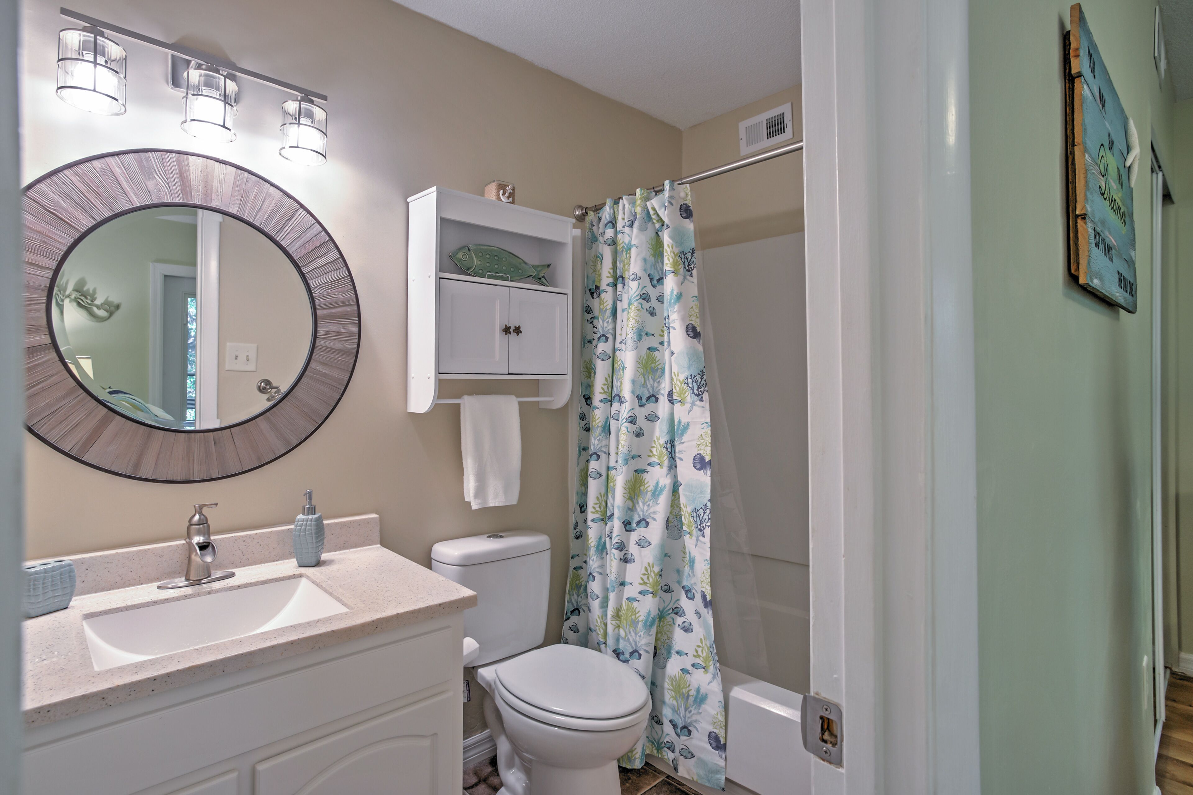 A bathroom with a round mirror, a sink, a toilet, and a shower curtain.