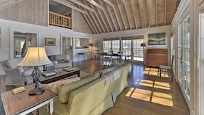 A spacious living area with a high wooden ceiling, a dining area, and large windows. - Waterfront Ipswich Escape: 2 Miles to Crane Beach! (Ipswich)