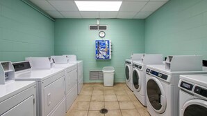 A laundry room with multiple washing machines and dryers, a trash bin, and a clock on the wall. - Bright PCB Condo w/ Gulf Views & Beach Access! (Panama City Beach)