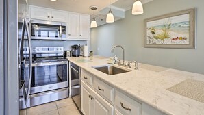 A modern kitchen with stainless steel appliances, white cabinetry, a marble countertop, and pendant lighting. - Bright PCB Condo w/ Gulf Views & Beach Access! (Panama City Beach)