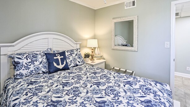 A bedroom with a bed, nightstand, lamp, and a mirror on the wall. - Bright PCB Condo w/ Gulf Views & Beach Access! (Panama City Beach)