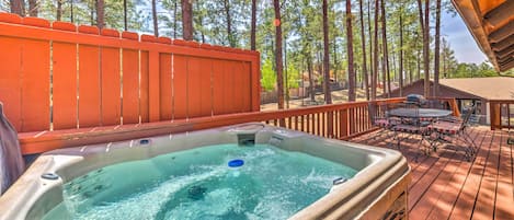 A hot tub on a wooden deck with a view of tall trees.