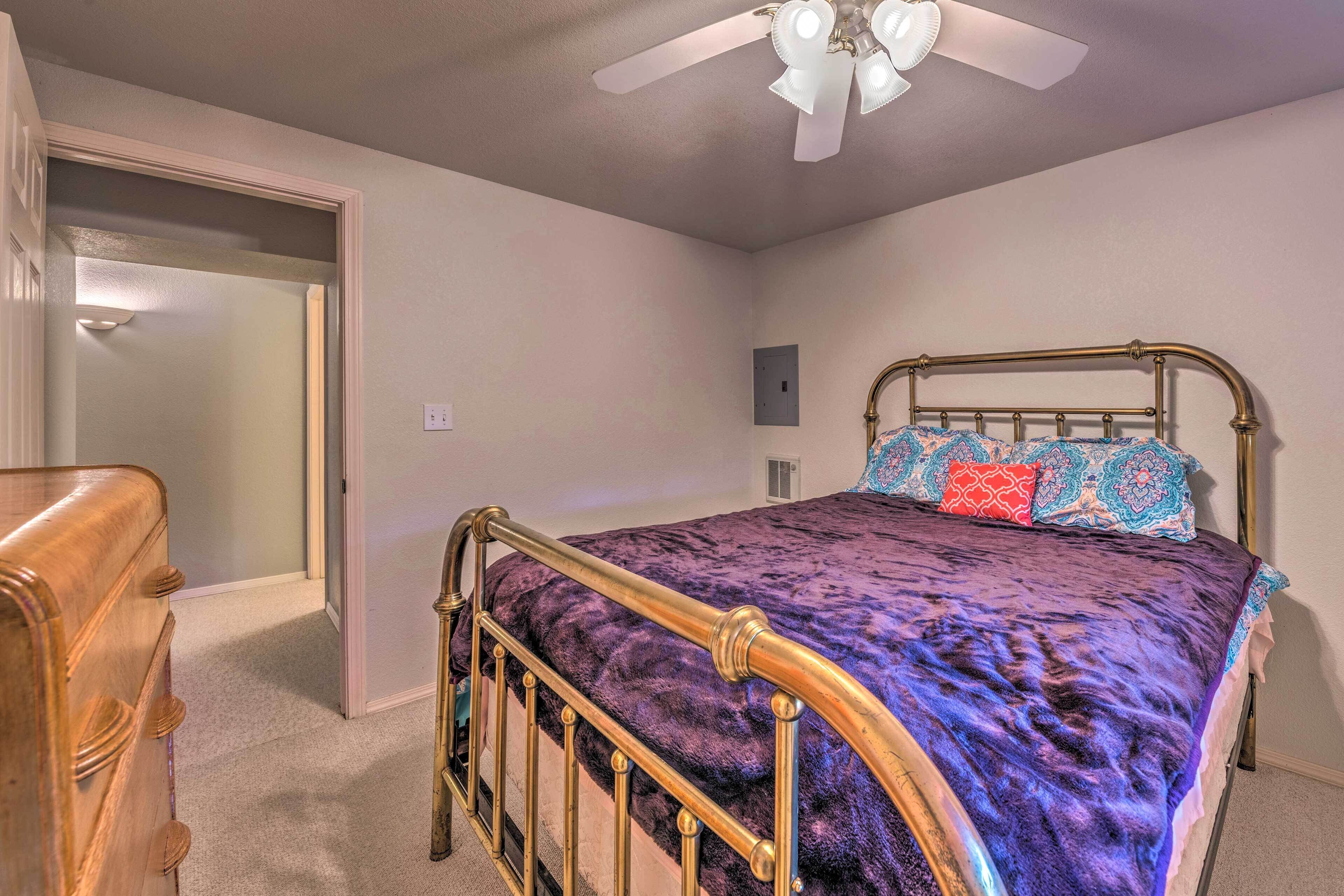 A bedroom with a bed, a ceiling fan, and a door leading to another room.