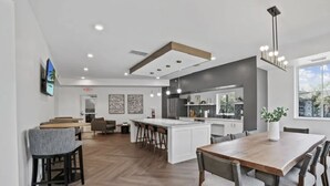 Una cocina moderna con una isla grande, taburetes de bar y una zona de comedor con una mesa y sillas de madera.