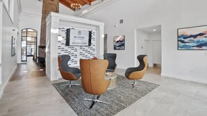 Un hall moderno con una recepción, dos sillones marrones, un tapete gris y un cartel de bienvenida enmarcado.