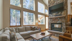 A spacious living room with a stone fireplace, large windows, and a cozy seating area. - Near Ski Access: Home w/ Hot Tub in Breck! (Breckenridge)