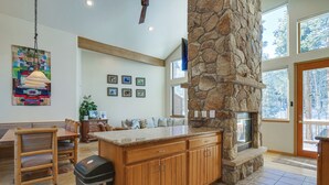 A spacious kitchen with a stone fireplace, wooden cabinets, and a large island. - Near Ski Access: Home w/ Hot Tub in Breck! (Breckenridge)