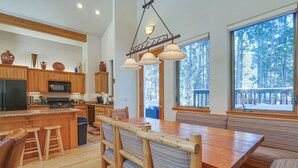 A spacious kitchen with wooden cabinets, a central island with stools, and a large dining table with bench seating. - Near Ski Access: Home w/ Hot Tub in Breck! (Breckenridge)