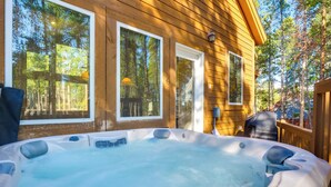 A hot tub on a wooden deck with large windows overlooking a forest. - Near Ski Access: Home w/ Hot Tub in Breck! (Breckenridge)