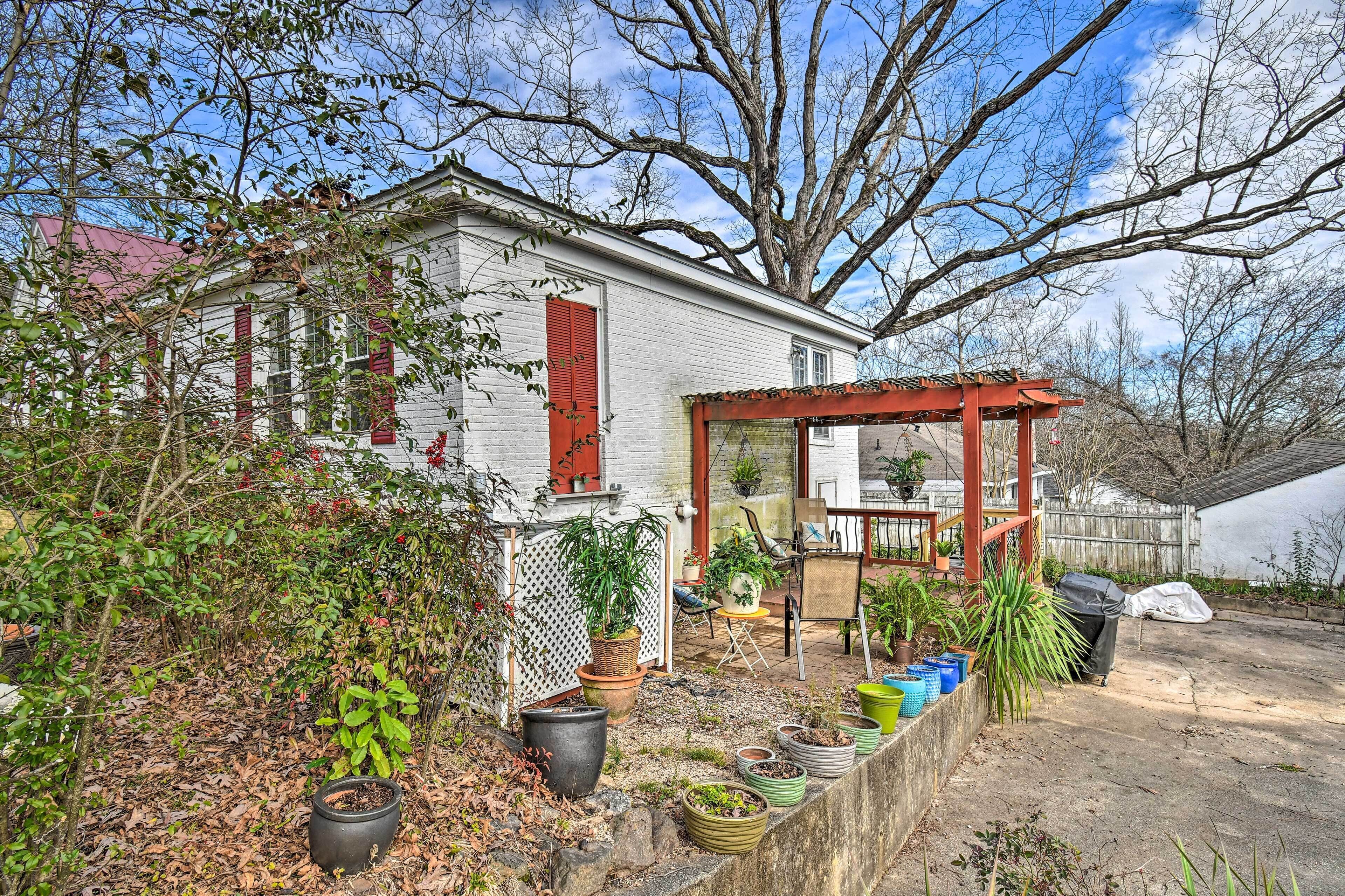 A house with a red porch, a white exterior, and a garden with various potted plants.
