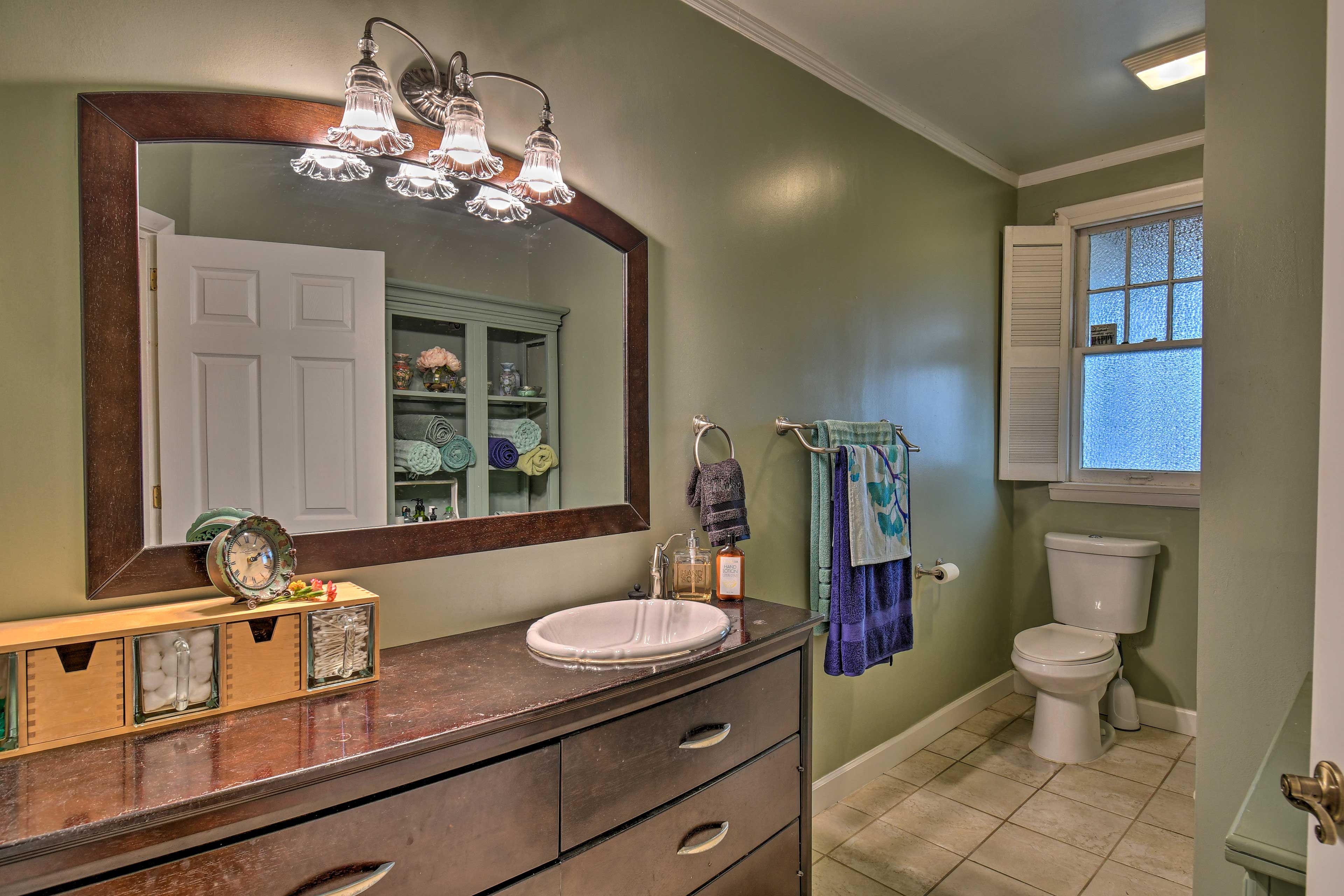 Une salle de bain avec un grand miroir, un lavabo et des toilettes.
