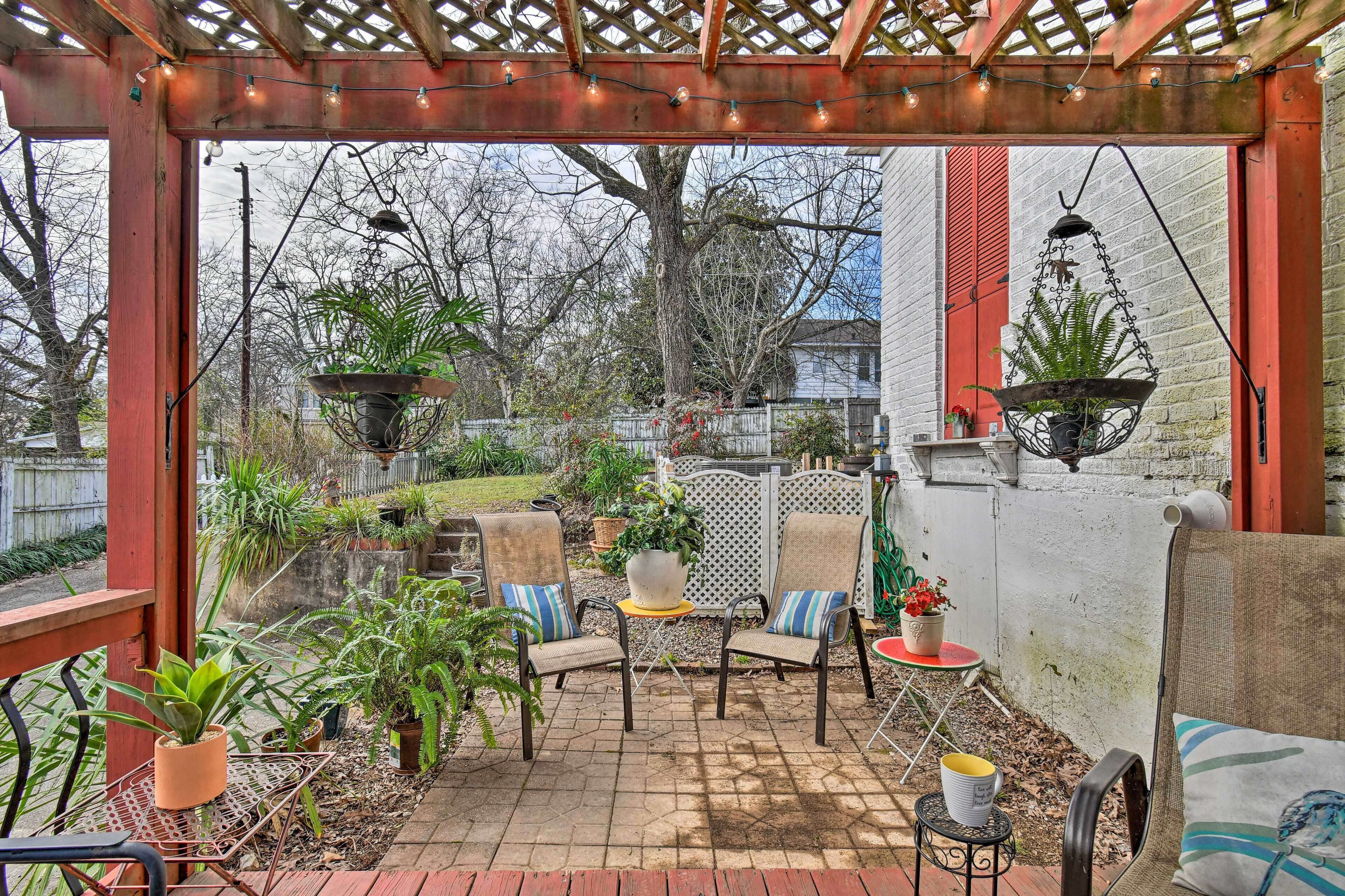Eine überdachte Terrasse mit Sitzgelegenheiten, Kübelpflanzen und Blick auf den Garten.