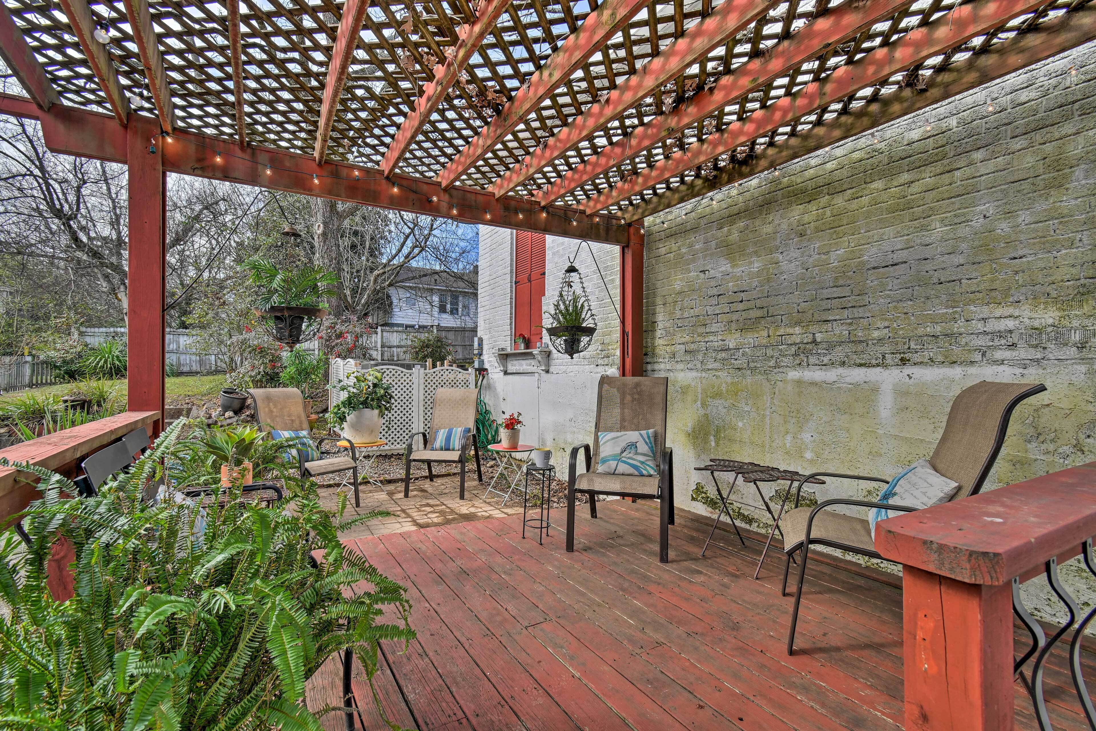 A covered patio with wooden flooring, outdoor furniture, and a brick wall.