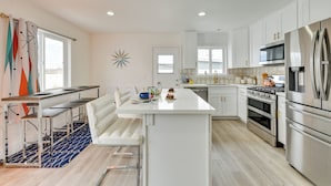 A modern kitchen with white cabinetry, stainless steel appliances, a central island, and a blue patterned rug. - Pool & Mountain Views: Palm Springs Home (Palm Springs)
