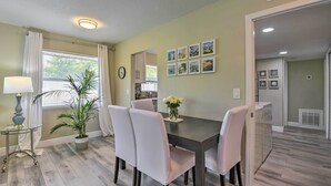 A dining area with a dark wooden table, white chairs, a potted plant, and a vase of flowers. - 3 Blocks to the Coast! Cozy Sarasota Retreat (Sarasota)