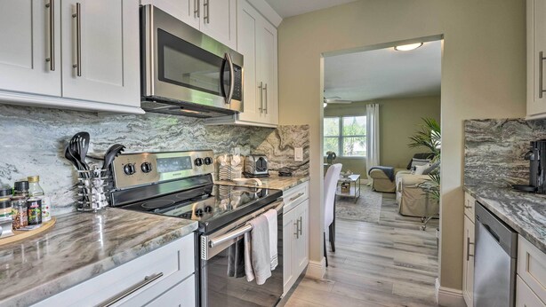A modern kitchen with white cabinets, a stainless steel microwave, a built-in oven, and a marble countertop. - 3 Blocks to the Coast! Cozy Sarasota Retreat (Sarasota)