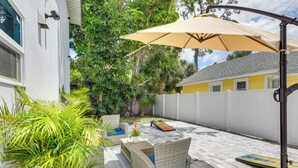 A patio area with wicker furniture, a large umbrella, and a white fence. - 3 Blocks to the Coast! Cozy Sarasota Retreat (Sarasota)