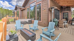 Eine Holzterrasse mit Sitzgelegenheiten im Freien, darunter blaue Adirondack-Stühle und eine Feuerstelle.