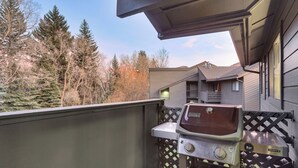 A covered outdoor grill area with a sink, surrounded by a wooden deck and lattice fence, overlooking a residential neighborhood. - Cozy Avon Condo w/ Grill: Walk to Ski Shuttle (Avon)
