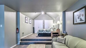 A cozy room with a sofa, a bed with a patterned bedspread, a wooden coffee table, and a framed picture on the wall. - Ruidoso Downs Condo w/ Mtn View + Balcony! (Ruidoso Downs)