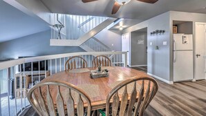A spacious dining area with a wooden table and chairs, a ceiling fan, and a staircase leading to an upper level. - Ruidoso Downs Condo w/ Mtn View + Balcony! (Ruidoso Downs)