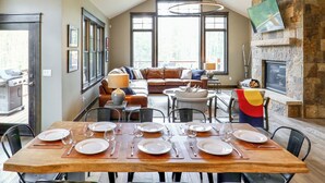 Un coin repas avec une table en bois dressée pour six personnes, entourée de chaises noires.