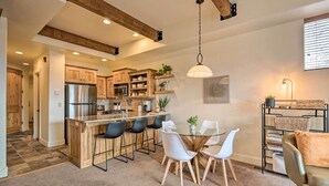 A modern kitchen with wooden cabinets, a stainless steel refrigerator, and a bar area with stools. - Walkable Park Mountain Getaway: Hot Tub & Views! (Park City)