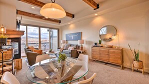 A modern living room with a glass dining table, sofas, and a fireplace. - Walkable Park Mountain Getaway: Hot Tub & Views! (Park City)