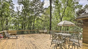 A wooden deck with outdoor furniture, surrounded by trees.
