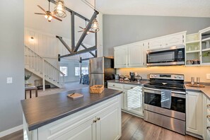 A modern kitchen with white cabinets, stainless steel appliances, and a dark countertop. - Centrally Located Pinedale Vacation Rental! (Pinedale)