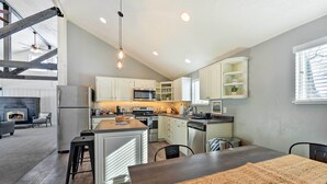 A modern kitchen with a central island, stainless steel appliances, and a dining area with a large rug. - Centrally Located Pinedale Vacation Rental! (Pinedale)