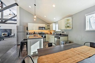 A modern kitchen with a central island, stainless steel appliances, and a dining area with a large rug.