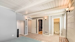 A bedroom with a bed, a bench, and a hallway leading to a bathroom. - Centrally Located Pinedale Vacation Rental! (Pinedale)