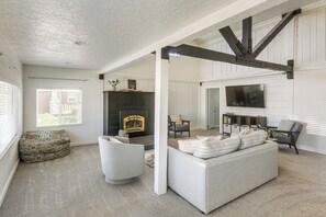 A living room with a fireplace, a sofa, a chair, and a television mounted on the wall. - Centrally Located Pinedale Vacation Rental! (Pinedale)