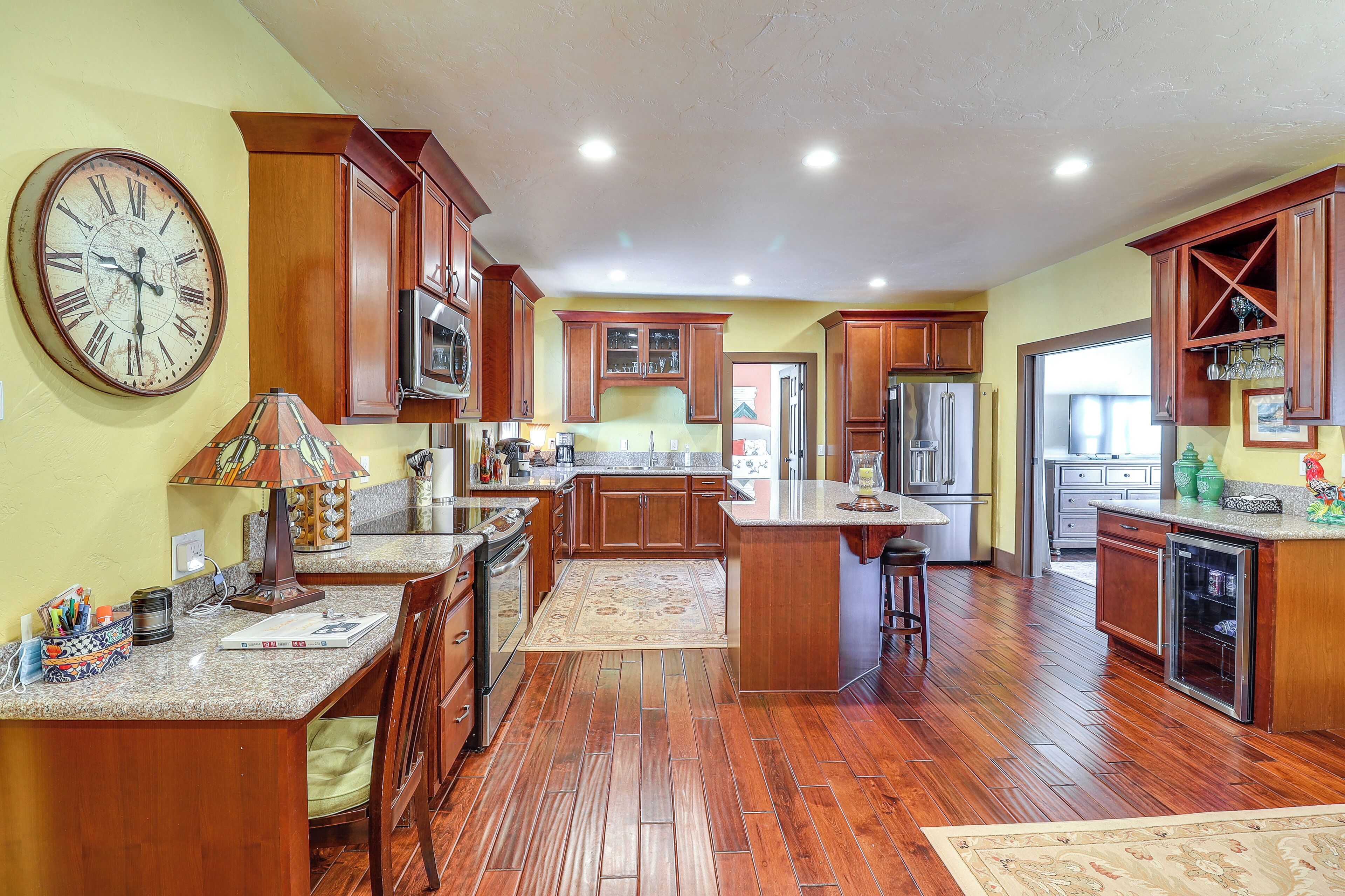 A spacious kitchen with wooden cabinets, a large clock, and a central island.