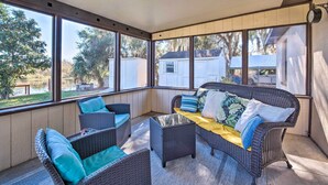 A covered patio area with wicker furniture and large windows.
