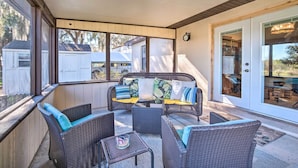 A covered patio area with wicker furniture, a clock on the wall, and a view of neighboring houses.