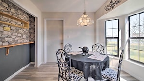 A dining area with a stone wall, a chandelier, and a view through large windows.