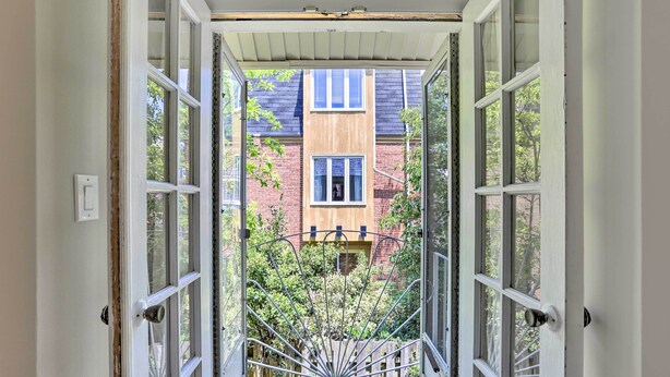 A view through an open doorway into a building with a brick facade and multiple windows.