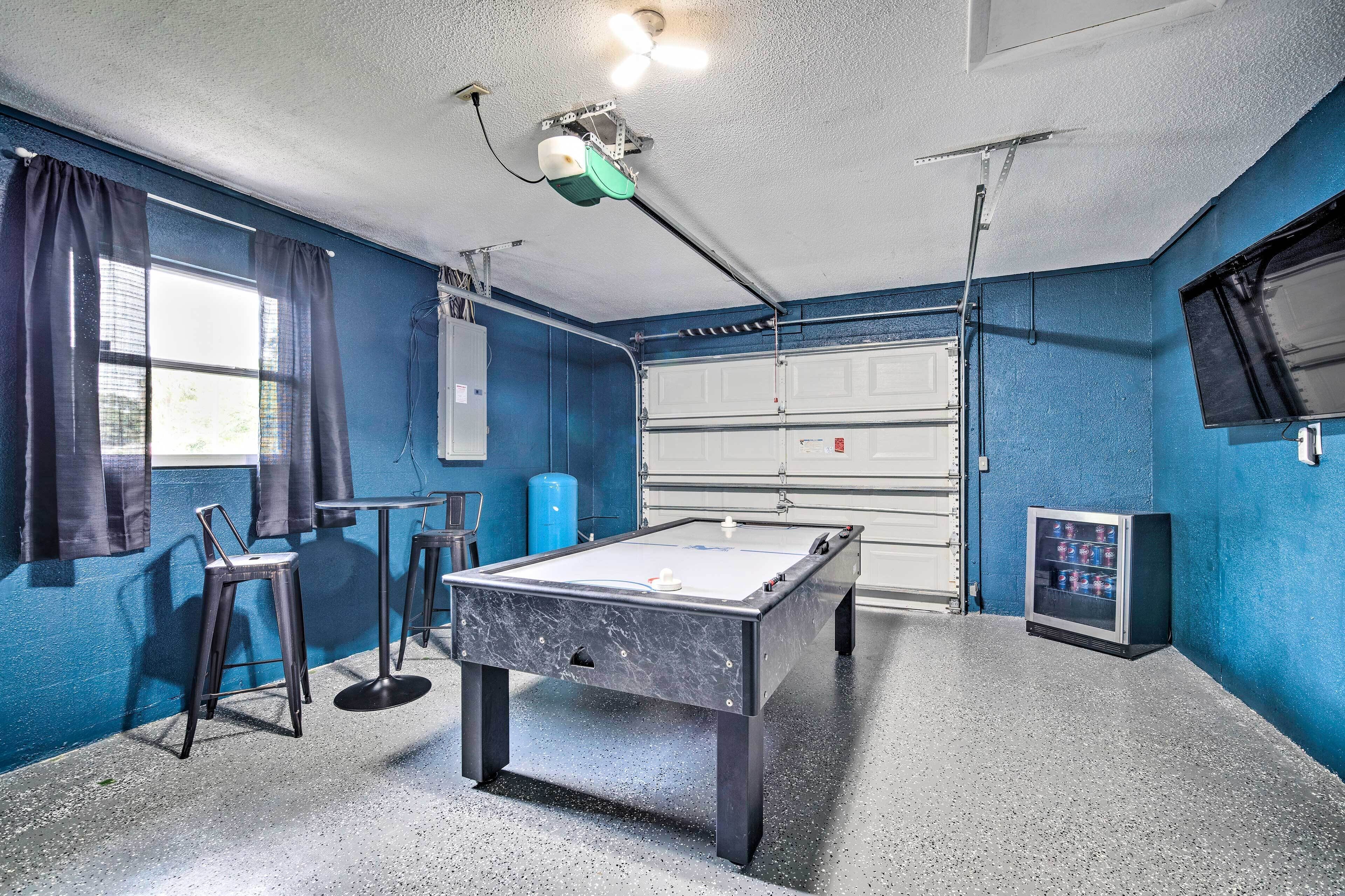 A pool table in a room with blue walls, a ceiling fan, and a window with curtains.