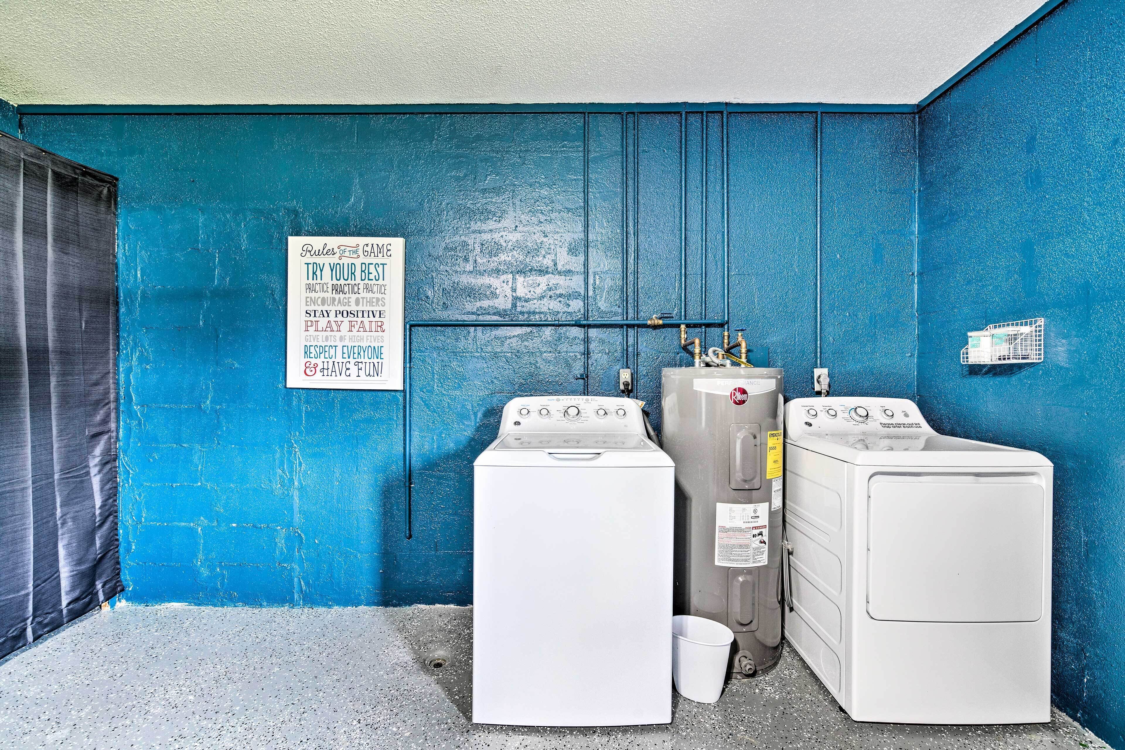 A laundry room with two washing machines, a sign with motivational phrases, and a blue wall.
