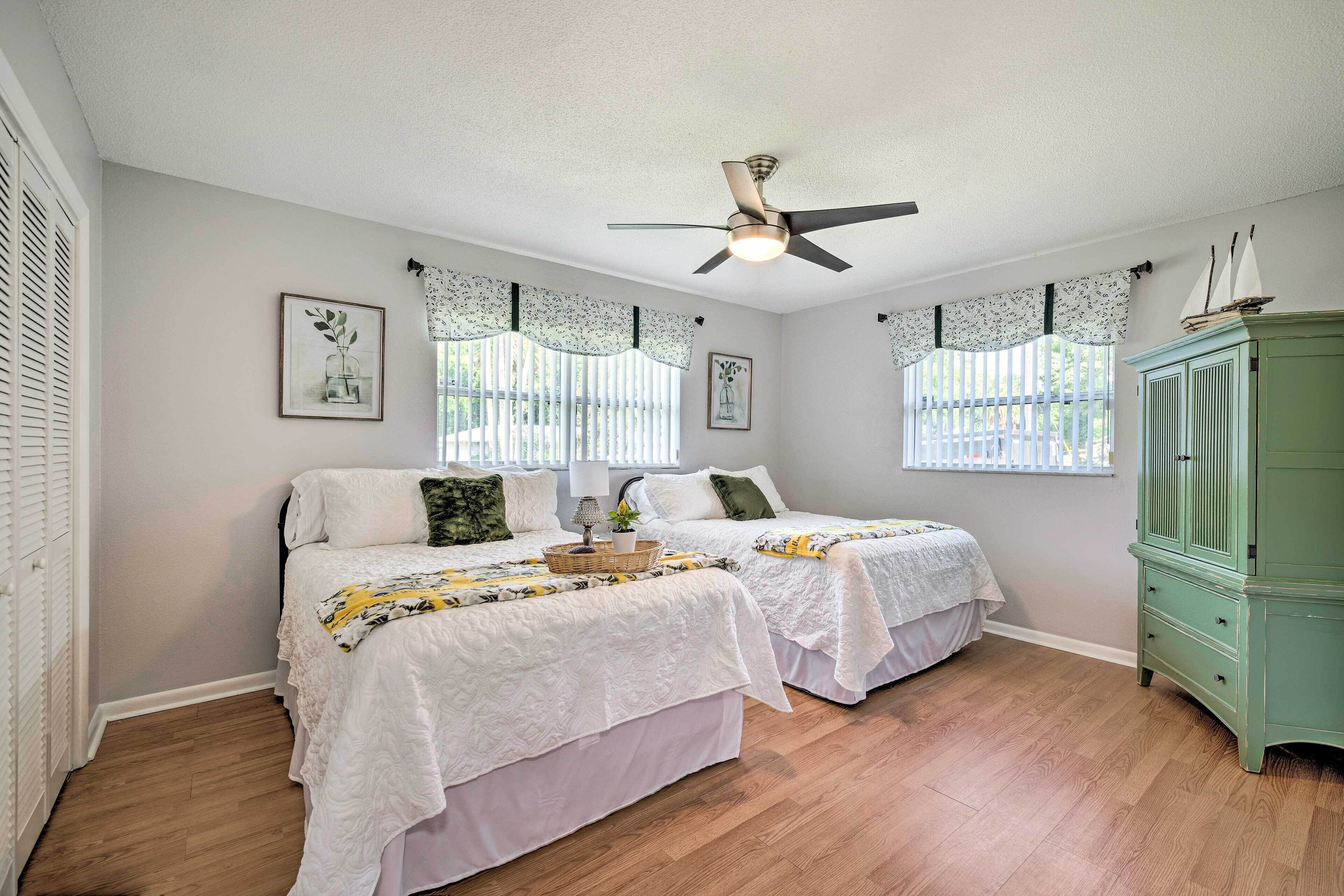 A bedroom with two beds, a ceiling fan, and a green cabinet.