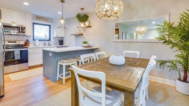 A modern kitchen with white cabinets, a wooden dining table, and a large island. - Seabrook Island Golf Resort Condo Near Beach! (Seabrook Island)