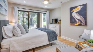 A bedroom with a bed, a ceiling fan, a large window, a painting, and a dresser. - Seabrook Island Golf Resort Condo Near Beach! (Seabrook Island)