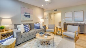 A modern living room with a grey sofa, a wooden coffee table, and a ceiling fan. - Seabrook Island Golf Resort Condo Near Beach! (Seabrook Island)