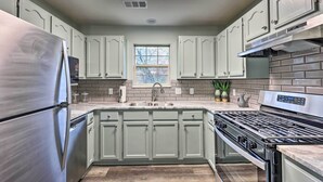 Eine moderne Küche mit einem Edelstahl-Kühlschrank, einem eingebauten Backofen und einem Spülbecken mit Fenster darüber.