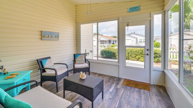 A sunlit room with a ceiling fan, wicker furniture, and a view through a glass door. - The Villages 2BR Vacation Home, Lanai & Golf Cart (The Villages)